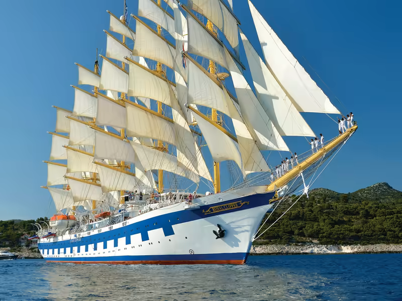 Royal Clipper under all 42 sails off a wooded Adriatic coastline